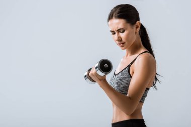 gri izole dambıl kullanarak çekici esmer sporcu