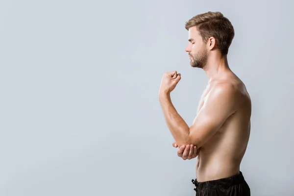 灰色で隔離された肘の痛みを持つスポーツマンの側面図 — ストック写真