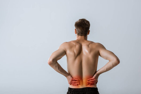 back view of shirtless sportsman with lower back pain isolated on grey