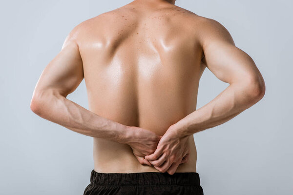 back view of shirtless sportsman with lower back pain isolated on grey