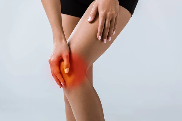 裁剪视图的女运动员与膝盖疼痛隔离在灰色 — 图库照片
