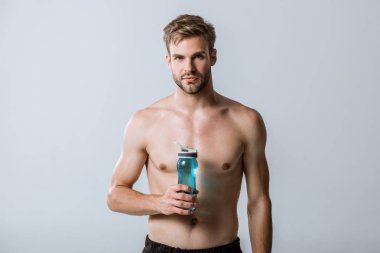 gri izole spor şişesi tutan gömleksiz sakallı sporcu ön görünümü