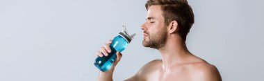 panoramic shot of shirtless bearded sportsman holding sport bottle isolated on grey clipart