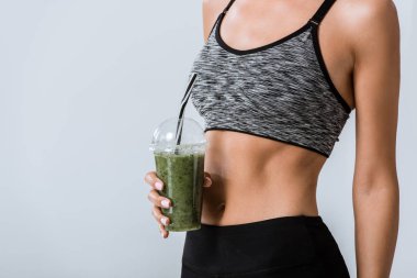 gri üzerinde izole smoothie tutan sporcu kısmi görünümü