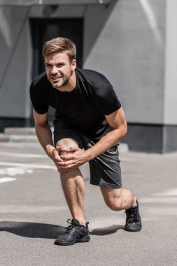 sokakta diz ağrısı ile siyah t-shirt sakallı sporcu