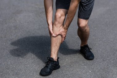 sokakta bacak ağrısı ile siyah spor ayakkabı sporcu kısmi görünümü