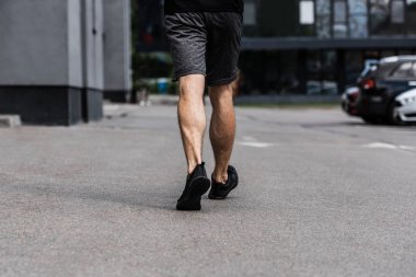 sokakta yürüyen siyah spor ayakkabılı sporcunun kısmi görünümü