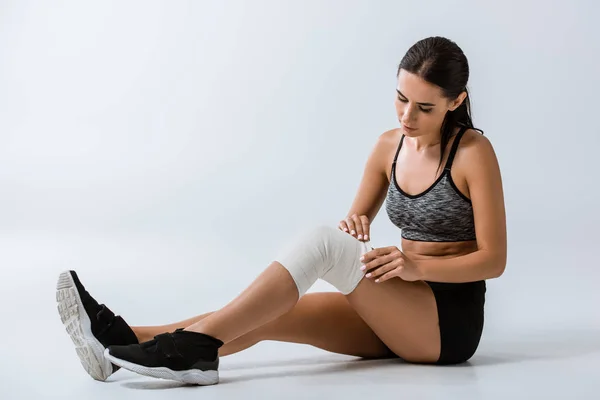 Sportvrouw Met Elastische Bandage Knie Zittend Grijs — Stockfoto