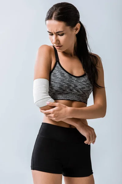 灰色で隔離された肘に弾性包帯を持つスポーツウーマン — ストック写真