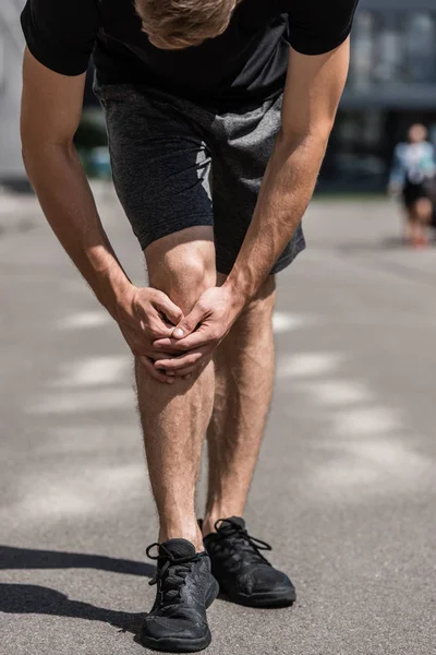 路上で膝の痛みを持つスポーツマンの部分的なビュー — ストック写真