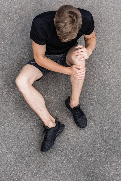 路上で膝の痛みを持つスポーツマンの頭上のビュー — ストック写真