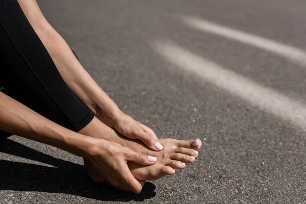 赤脚女运动员与脚痛在街上的部分视图 — 图库照片