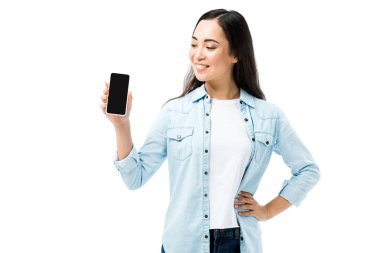 Kot gömlekli çekici ve gülümseyen Asyalı kadın elinde beyaz üzerinde kopya alanı olan akıllı telefon tutuyor. 