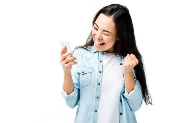 Kot gömlekli çekici ve gülümseyen Asyalı kadın evet işareti yapıyor ve akıllı telefonu beyazın üzerinde yalnız tutuyor. 