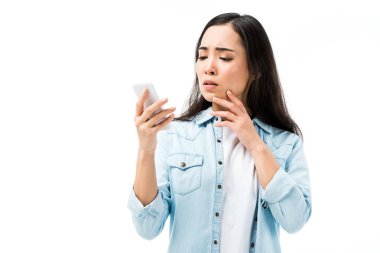 Kotlu tişörtlü çekici ve şok olmuş Asyalı kadın elinde akıllı telefon, beyaz üzerinde izole halde. 