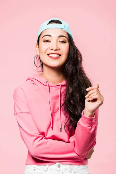 穿着粉色套头衫和帽子的迷人的亚洲女人 在粉色上孤零零地笑着 — 图库照片