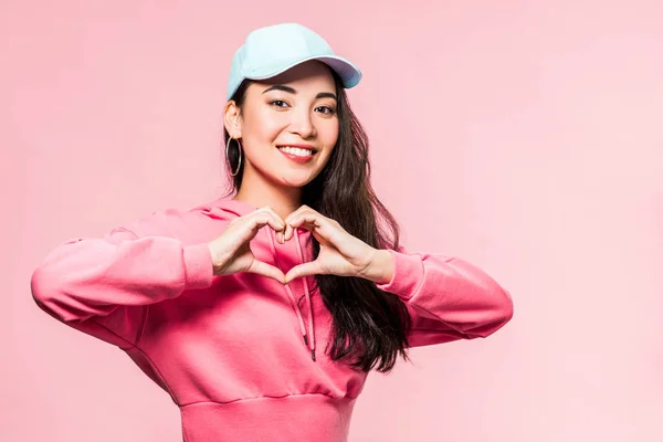 Atraente Asiático Mulher Rosa Pulôver Cap Sorrindo Mostrando Coração Símbolo — Fotografia de Stock
