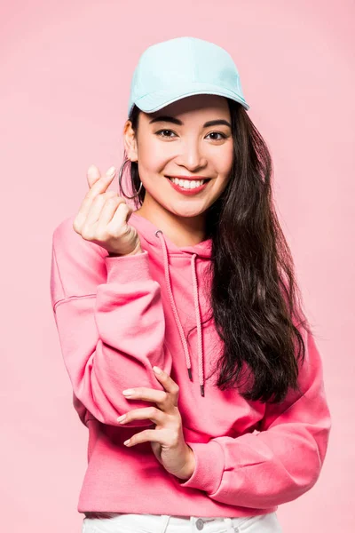 Atraente Asiático Mulher Rosa Pulôver Cap Sorrindo Mostrando Coração Símbolo — Fotografia de Stock