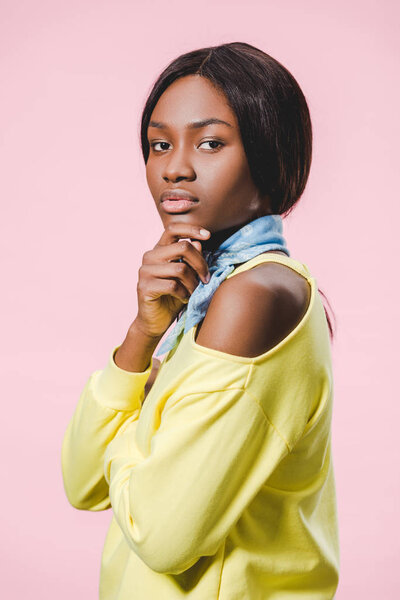 attractive african american woman in blue scarf looking at camera isolated on pink