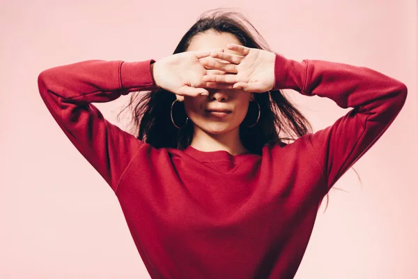 woman in red sweater obscuring face isolated on pink