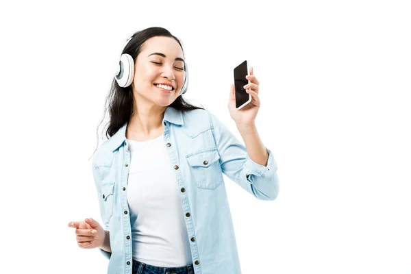 Atraente Sorridente Asiático Mulher Denim Camisa Ouvindo Música Segurando Smartphone — Fotografia de Stock