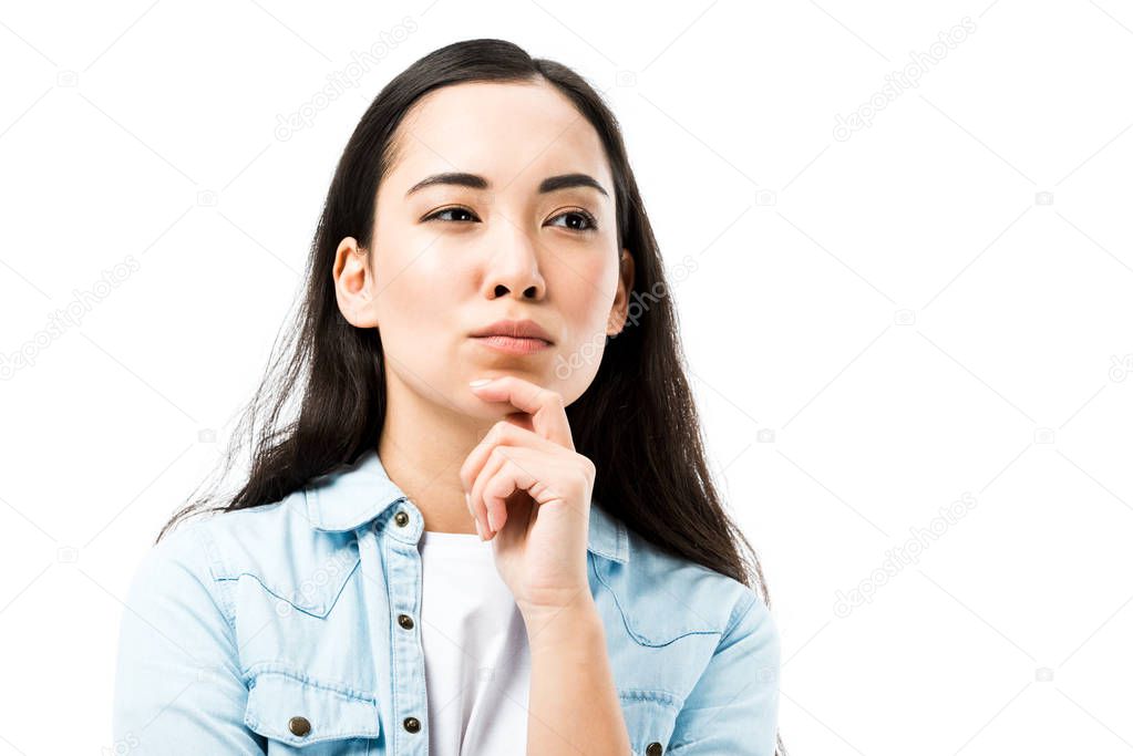 attractive and pensive asian woman in denim shirt looking away isolated on white 