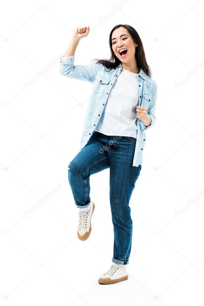 attractive and smiling asian woman in denim shirt showing yes gesture isolated on white 