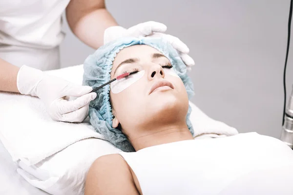 kirpik ustası gri izole model yüzünde sahte kirpik fırçalama