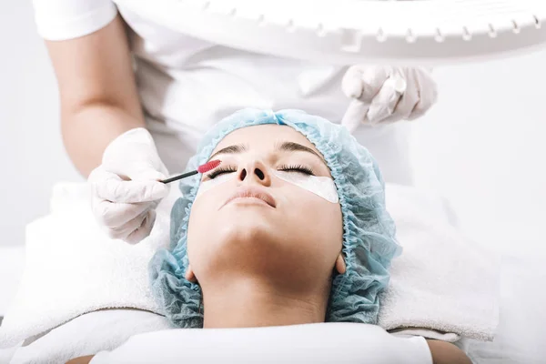 kirpik ustası beyaz izole model yüzünde sahte kirpik fırçalama