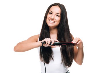 smiling brunette beautiful woman straightening long shiny hair with flat iron isolated on white clipart