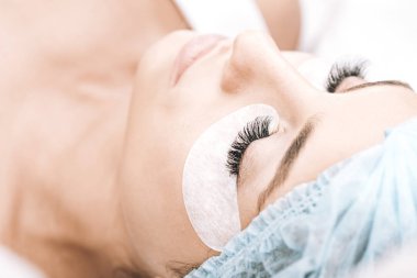 model with false eyelashes and closed eyes lying on couch after eyelash extensions