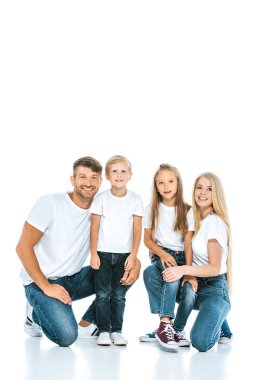 Beyaz kameraya bakarken gülümseyen neşeli bir aile.