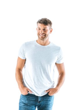 Elleri ceplerinde, beyazların üzerinde duran neşeli adam. 