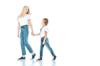 Mutlu anne çocukla el ele tutuşuyor ve beyaz üzerinde yürüyor. 