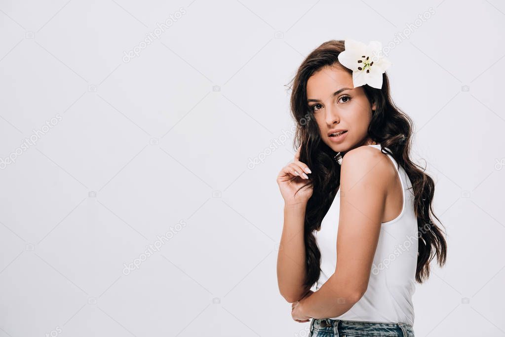 brunette beautiful woman with lily in long healthy hair isolated on grey