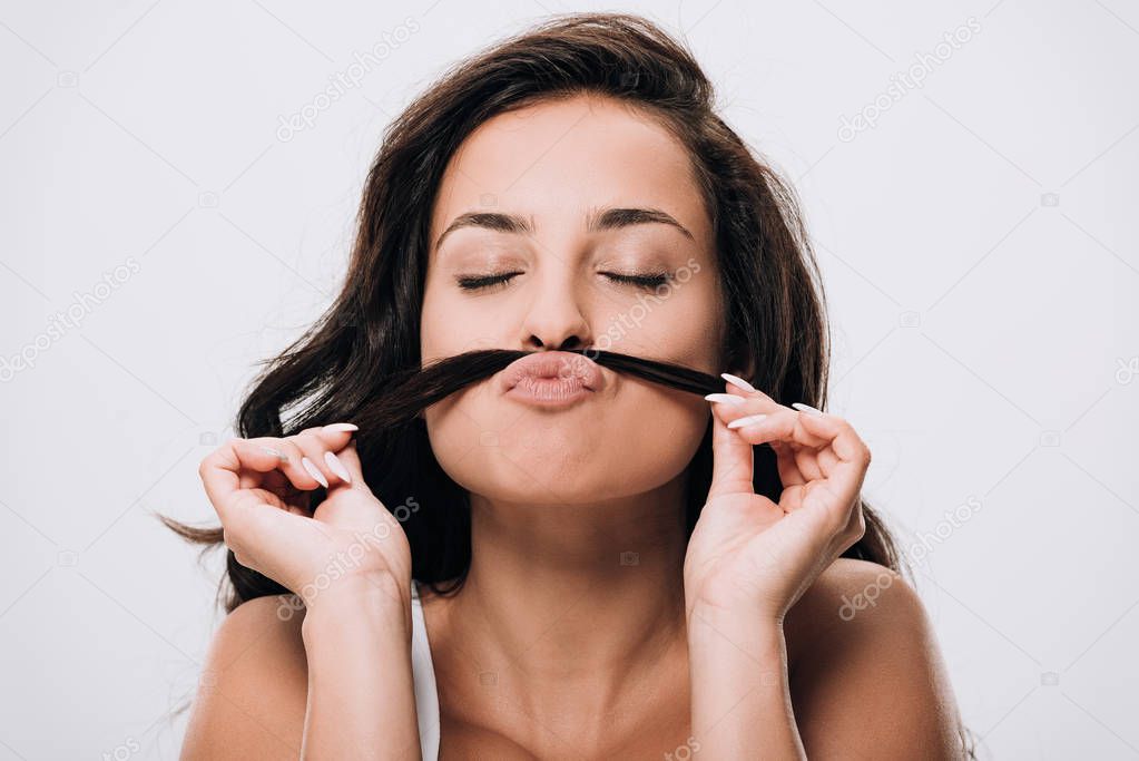 brunette beautiful woman with closed eyes making fake mustache from long healthy hair isolated on grey