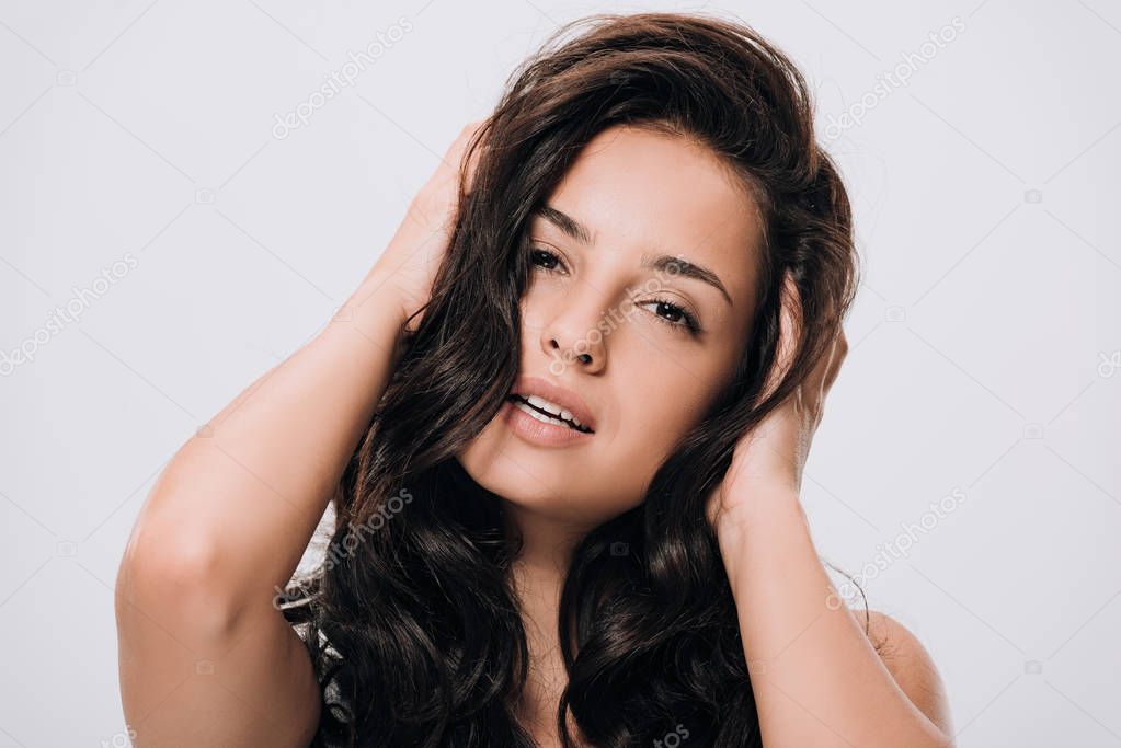 brunette beautiful woman touching long curly healthy hair isolated on grey