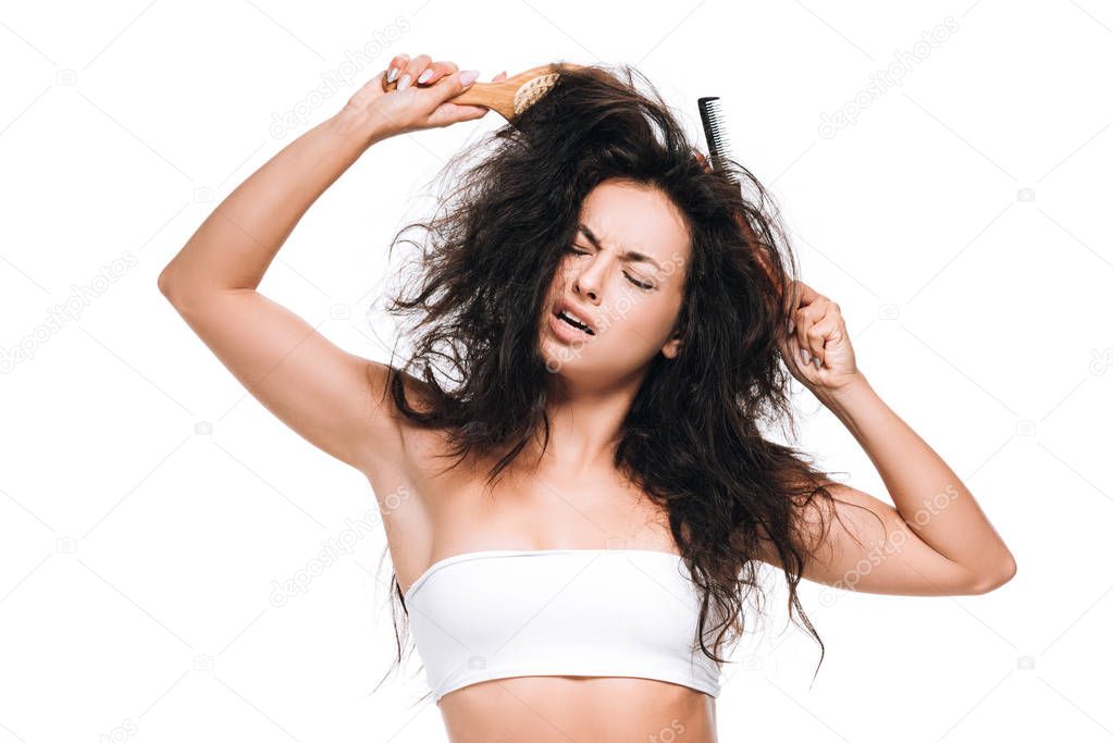 brunette woman with closed eyes and combs in wavy unruly hair isolated on white