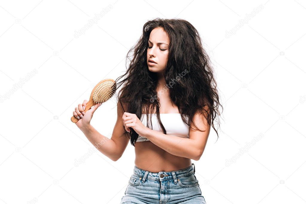 brunette woman styling unruly curly hair with hairbrush isolated on white