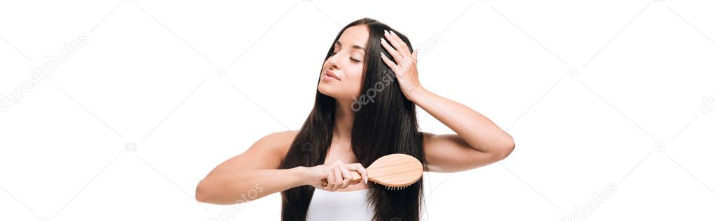 panoramic shot of brunette beautiful woman with closed eyes brushing long straight healthy and shiny hair with comb isolated on white