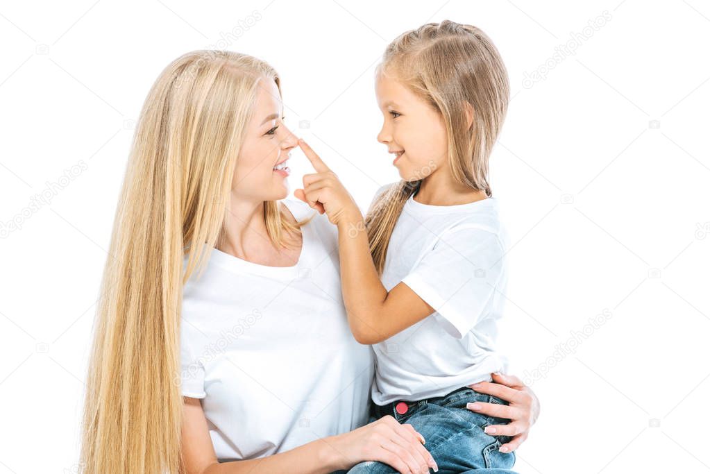 preteen daughter smiling and touching nose of mother isolated on white