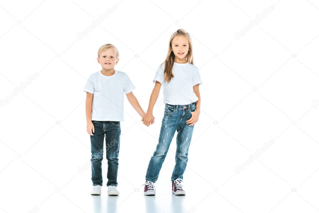cute kids holding hands and standing in blue jeans on white 