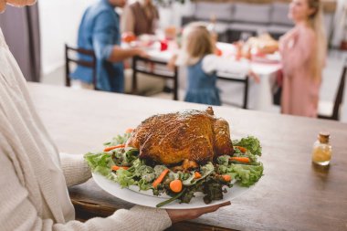 cropped view of grandmother holding plate with tasty turkey in Thanksgiving day   clipart