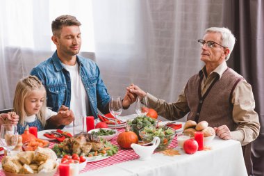 Baba, torun ve büyükbaba el ele tutuşup Şükran Günü 'ne burnunu sokuyor.    