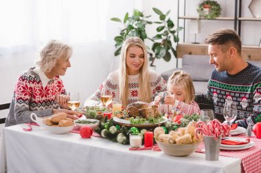Gülümseyen aile üyeleri masada oturuyor ve Noel 'i kutluyorlar 