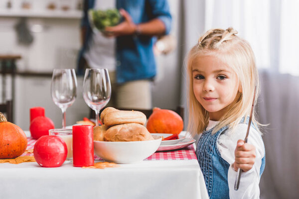 избирательный фокус милой дочери, держащей нож и улыбающейся в День Благодарения
 
