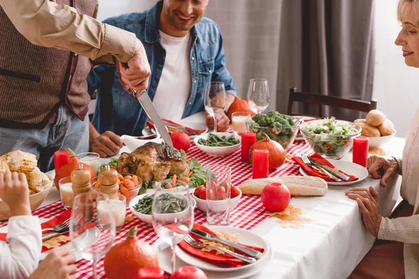 Abgeschnittene Ansicht Von Familienmitgliedern Die Tisch Sitzen Und Großvater Schneidet — Stockfoto