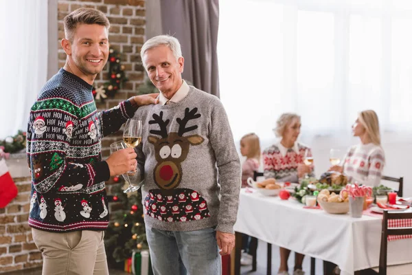 父と笑顔の祖父がワイングラスを持ってクリスマスにカメラを見て — ストック写真