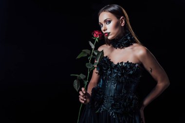 Siyah gotik elbiseli korkunç vampir kızın elinde siyah gül var.