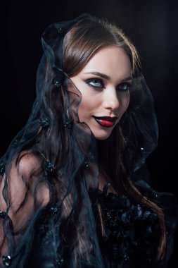 Siyah gotik elbiseli ve duvak takmış gülümseyen korkunç vampir kız.